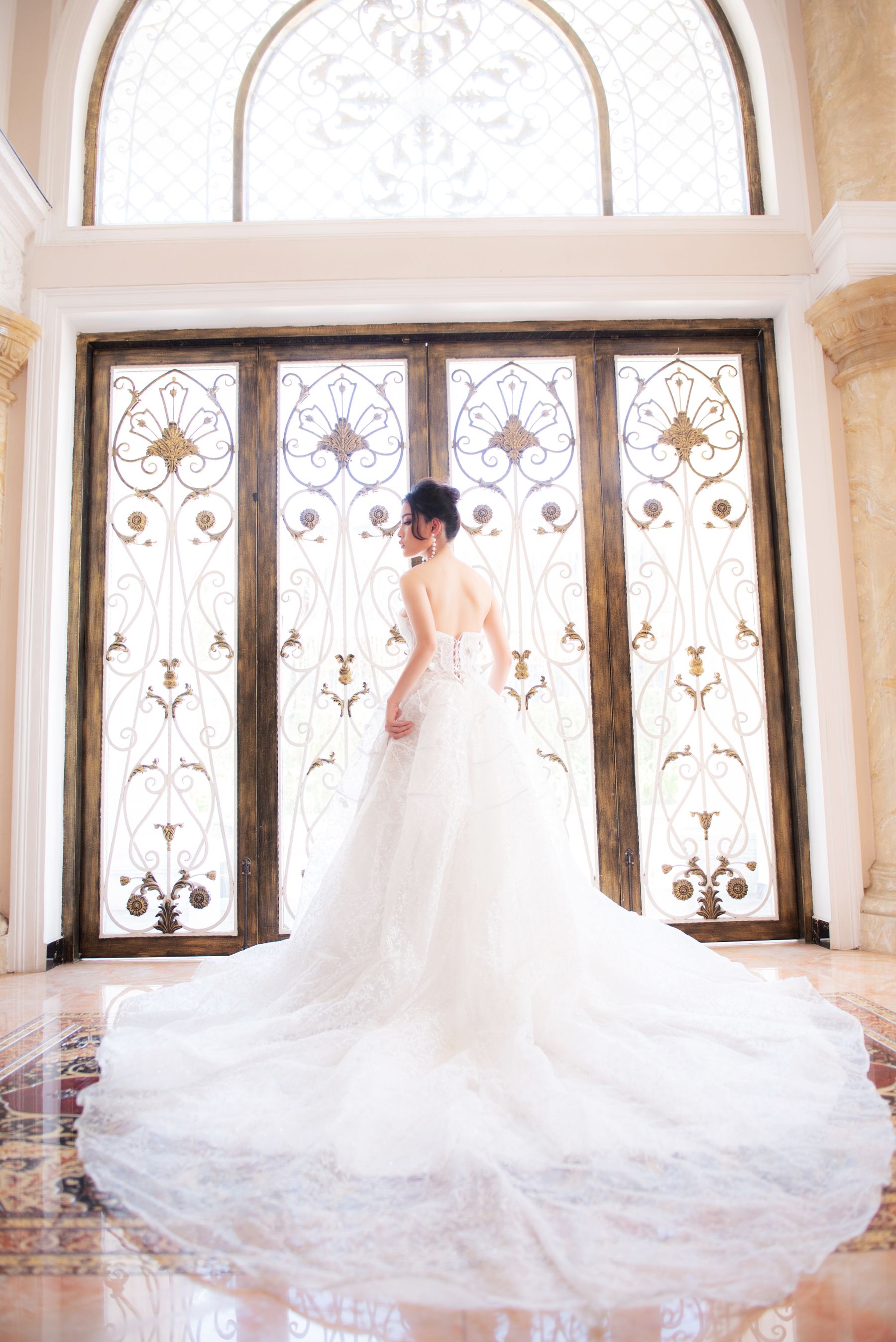 Bride in a lace gown photographed against an ornate window
